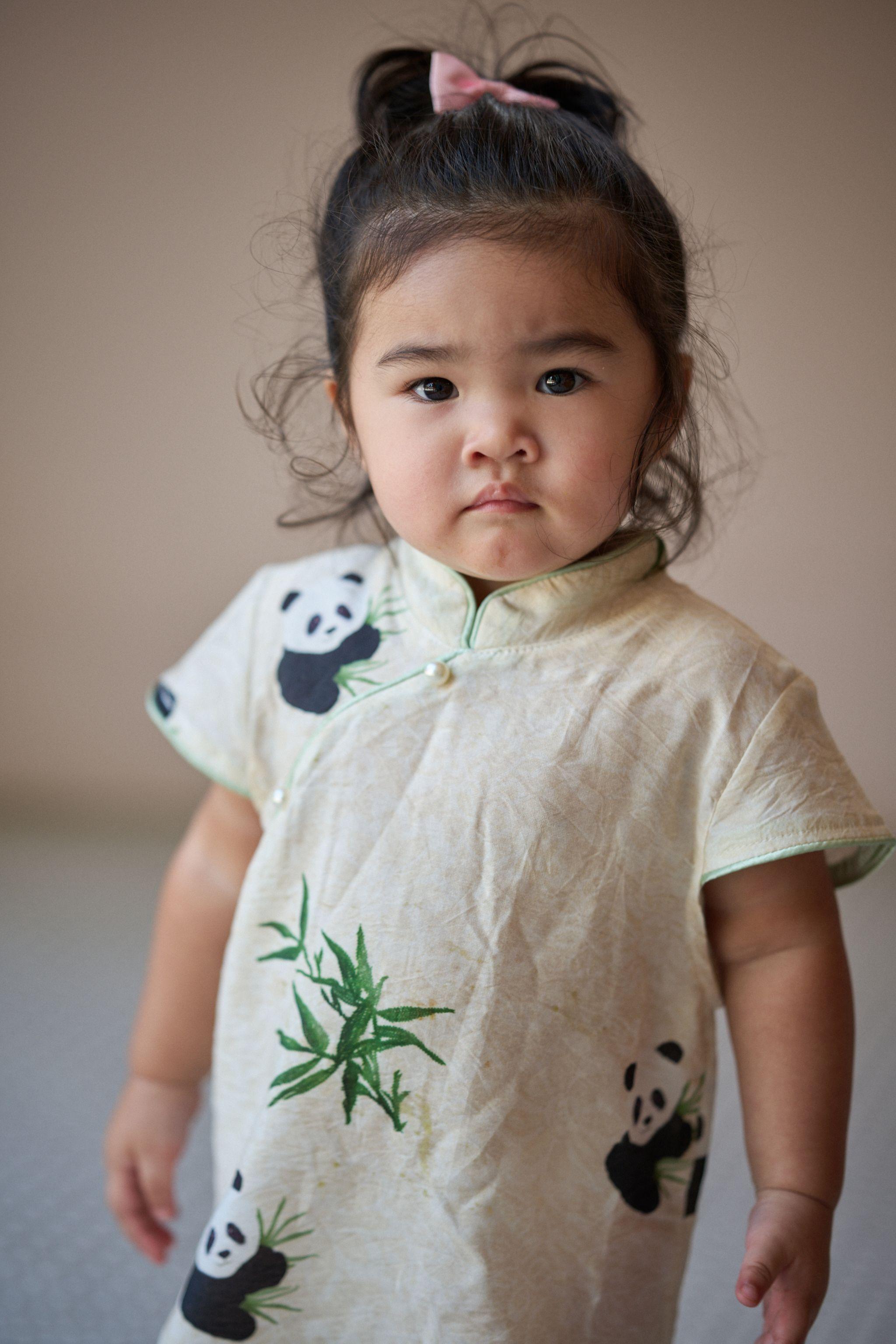 Toddler in a panda-print blouse standing among garden plants — Kids Portraits photography, Austin A toddler in a panda-print blouse standing among garden plants.