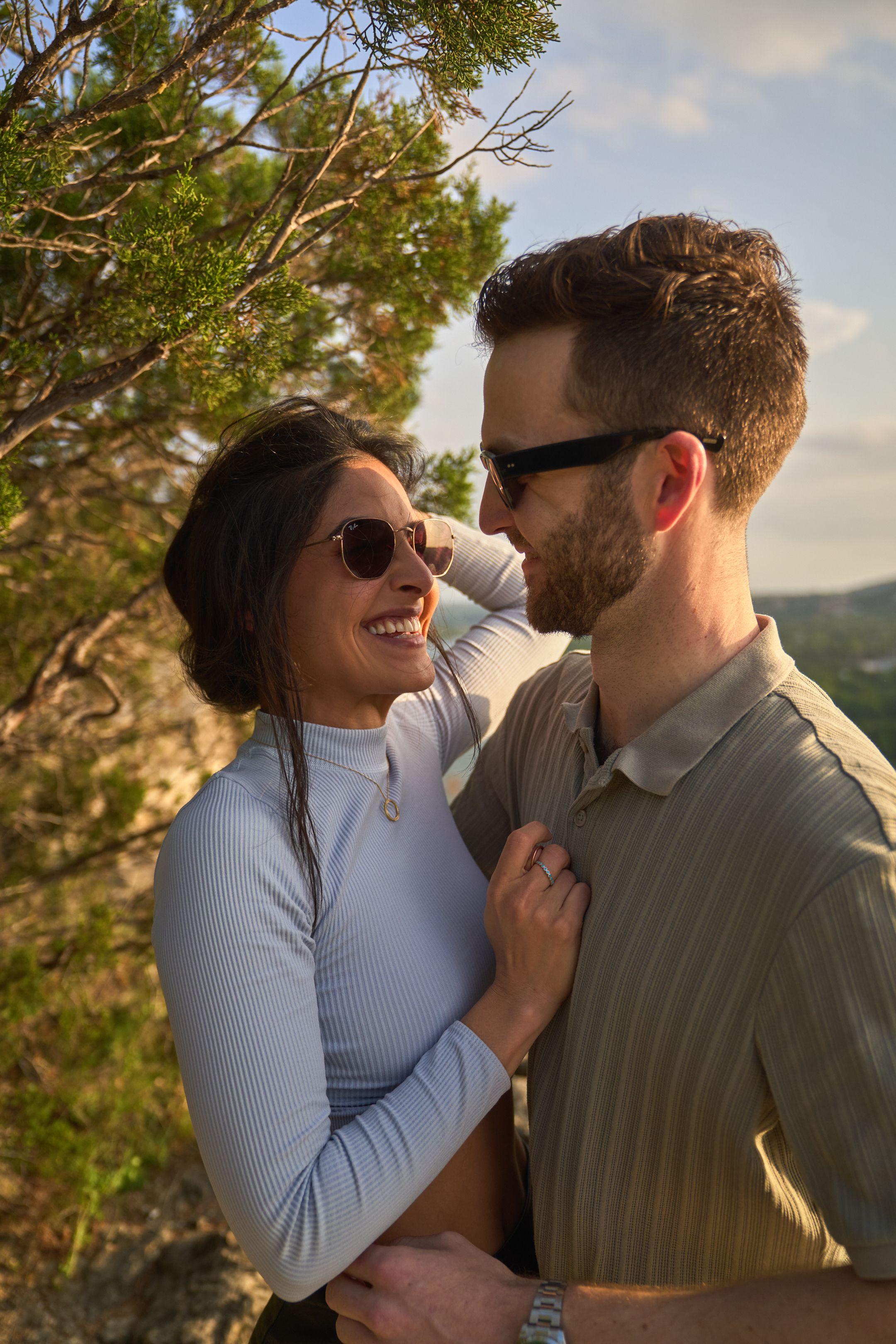 Newly engaged couple in sunglasses holding each other on the Mount Bonnell overlook — Engagement & Proposals photography, Austin A newly engaged couple in sunglasses holding each other on the Mount Bonnell overlook.