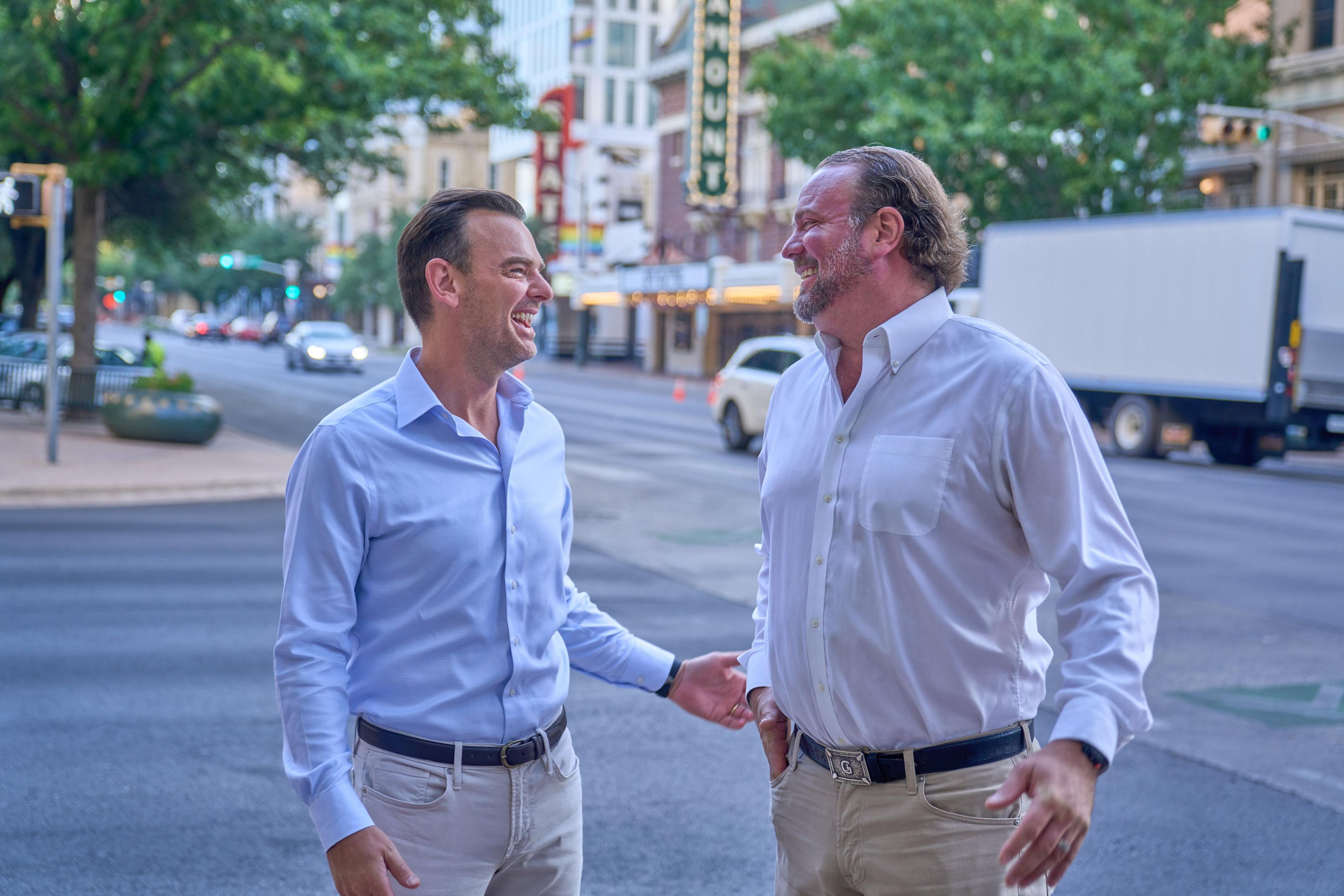 Two colleagues laughing together while walking along a downtown Austin street — Congress Avenue photography, Austin Two colleagues laughing together while walking along a downtown Austin street