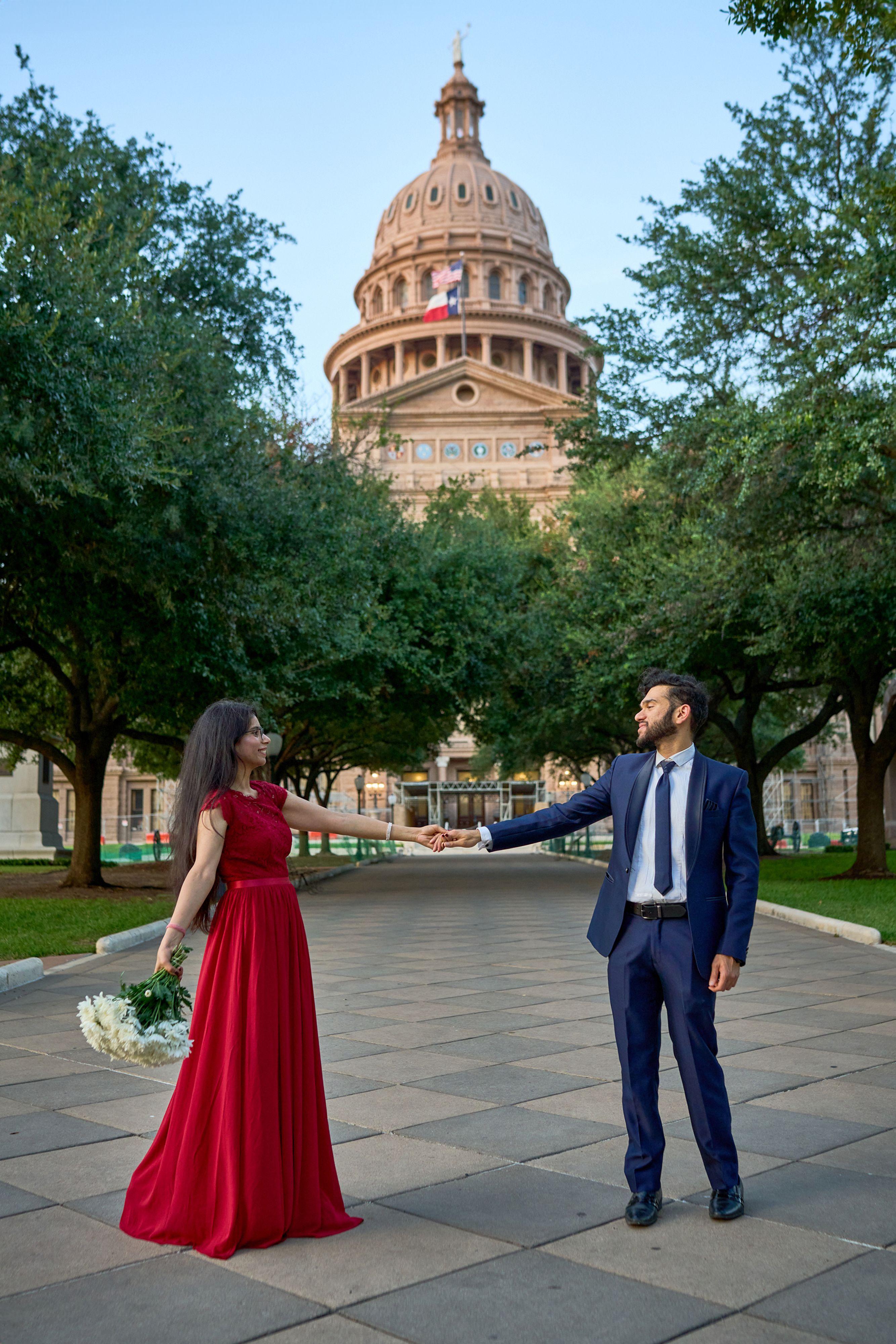 Bride in a red gown and her groom reaching for each other on the walk up to the Texas Capitol — Elopements photography, Austin A bride in a red gown and her groom reaching for each other on the walk up to the Texas Capitol.