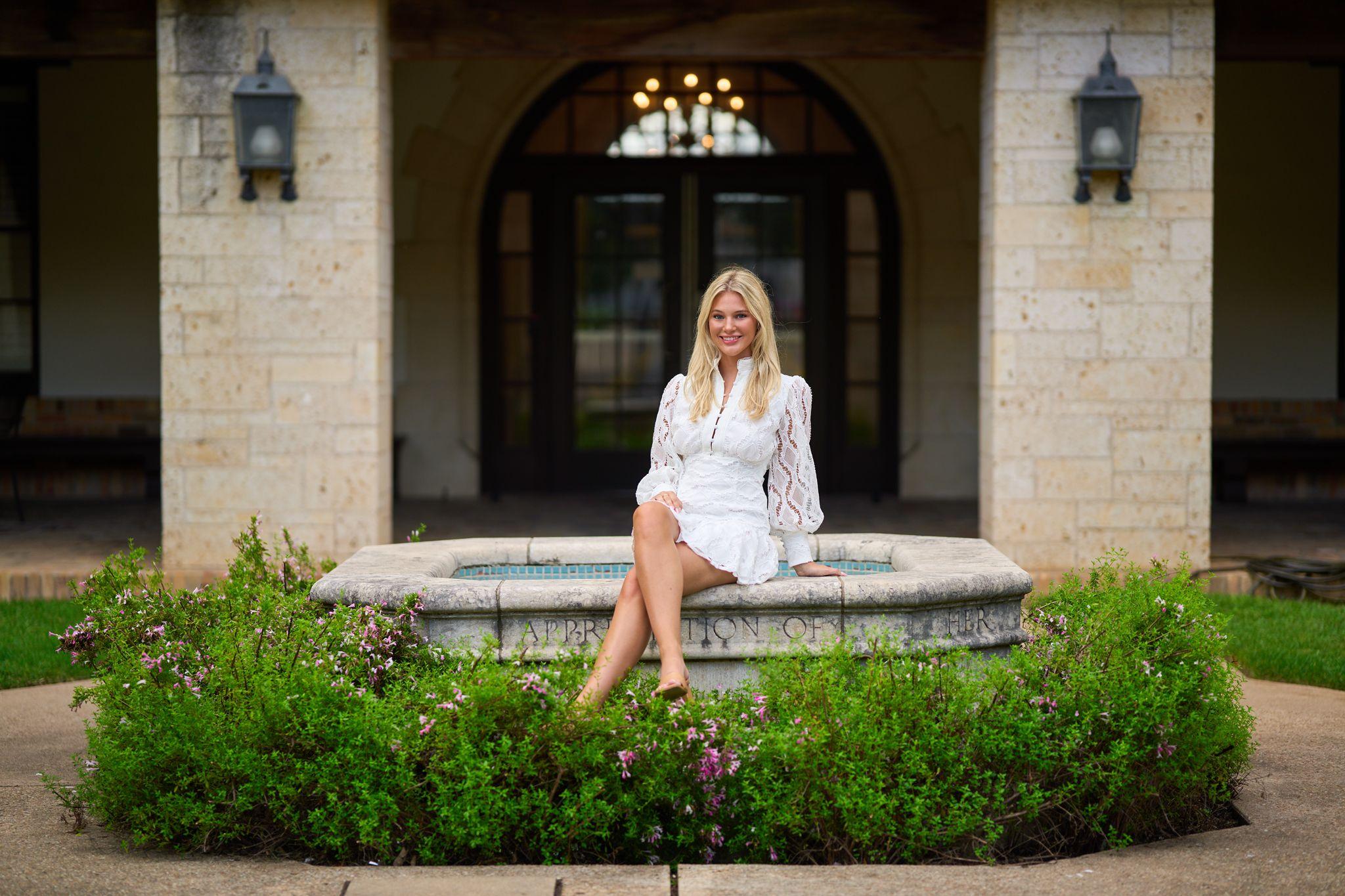 Woman in white seated on a stone bench outside an arched doorway — Portrait photography, Austin A woman in white seated on a stone bench outside an arched doorway.