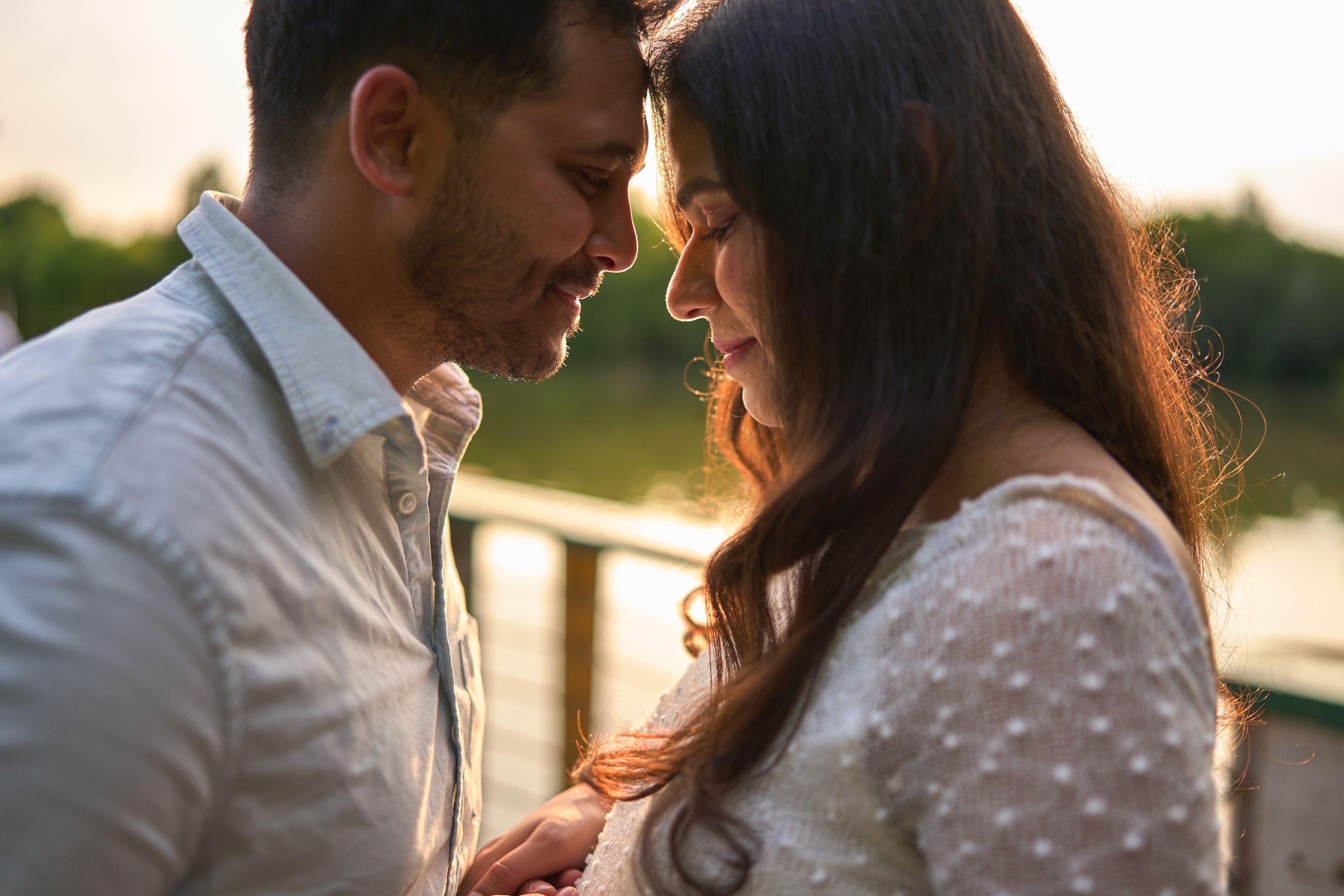 Couple standing forehead to forehead, backlit by low sun over the water — Couples & Anniversary photography, Austin A couple standing forehead to forehead, backlit by low sun over the water.