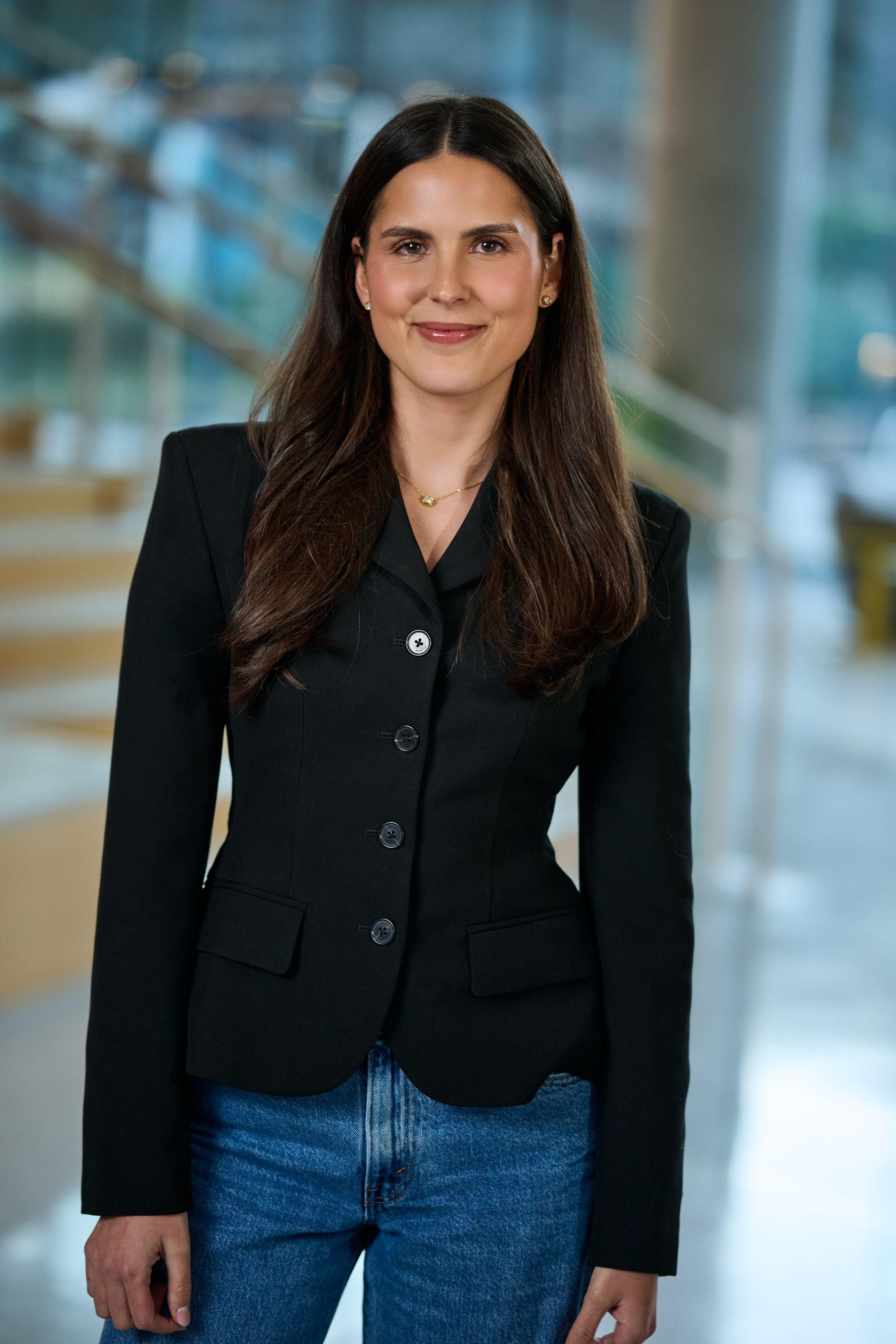 Woman in a black blazer and jeans standing in an office atrium — Business headshots, Austin A woman in a black blazer and jeans standing in an office atrium