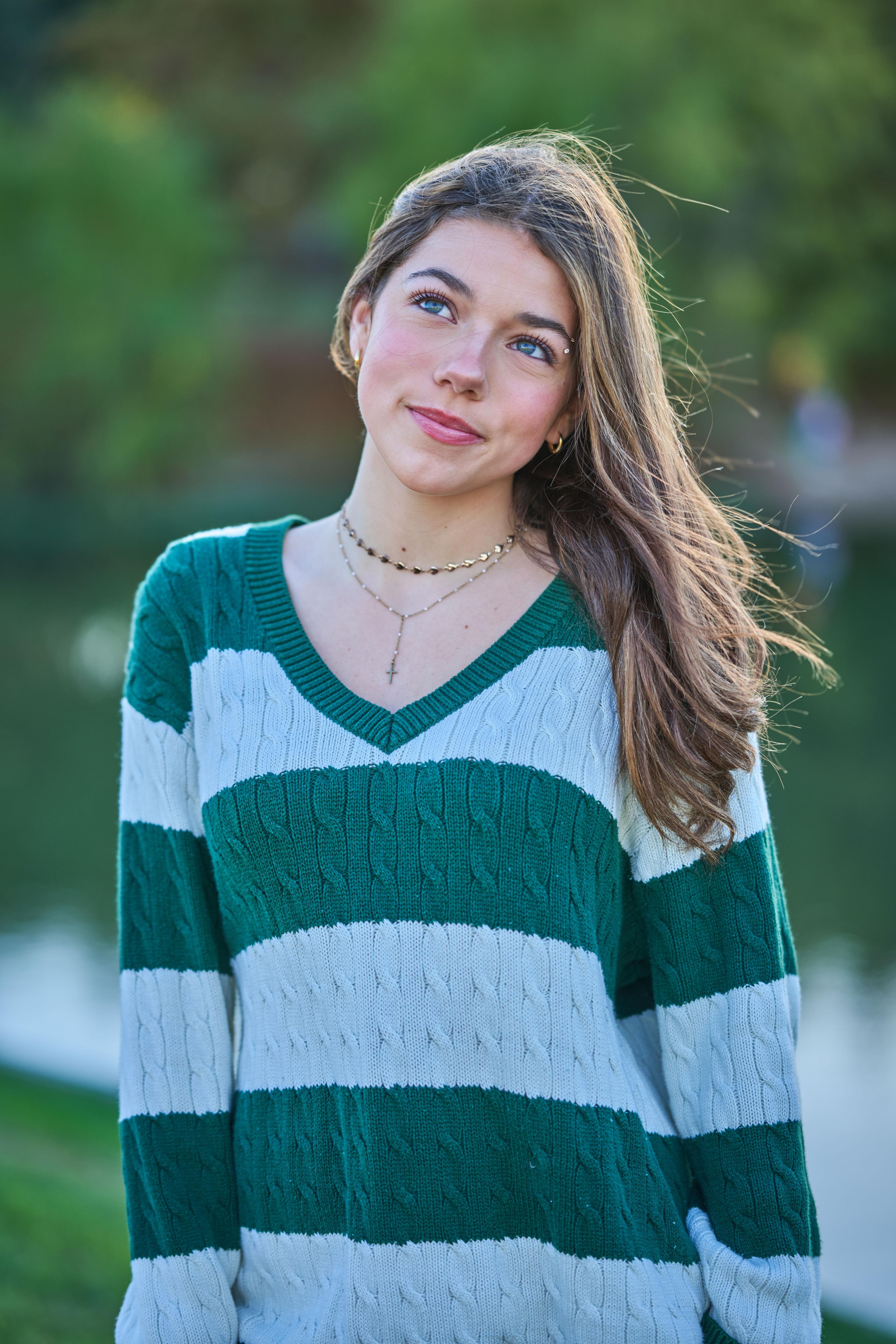 Young woman in a green and white striped rugby sweater standing in a park, hair moving — Fashion & editorial photography, Austin A young woman in a green and white striped rugby sweater standing in a park, hair moving in the wind.