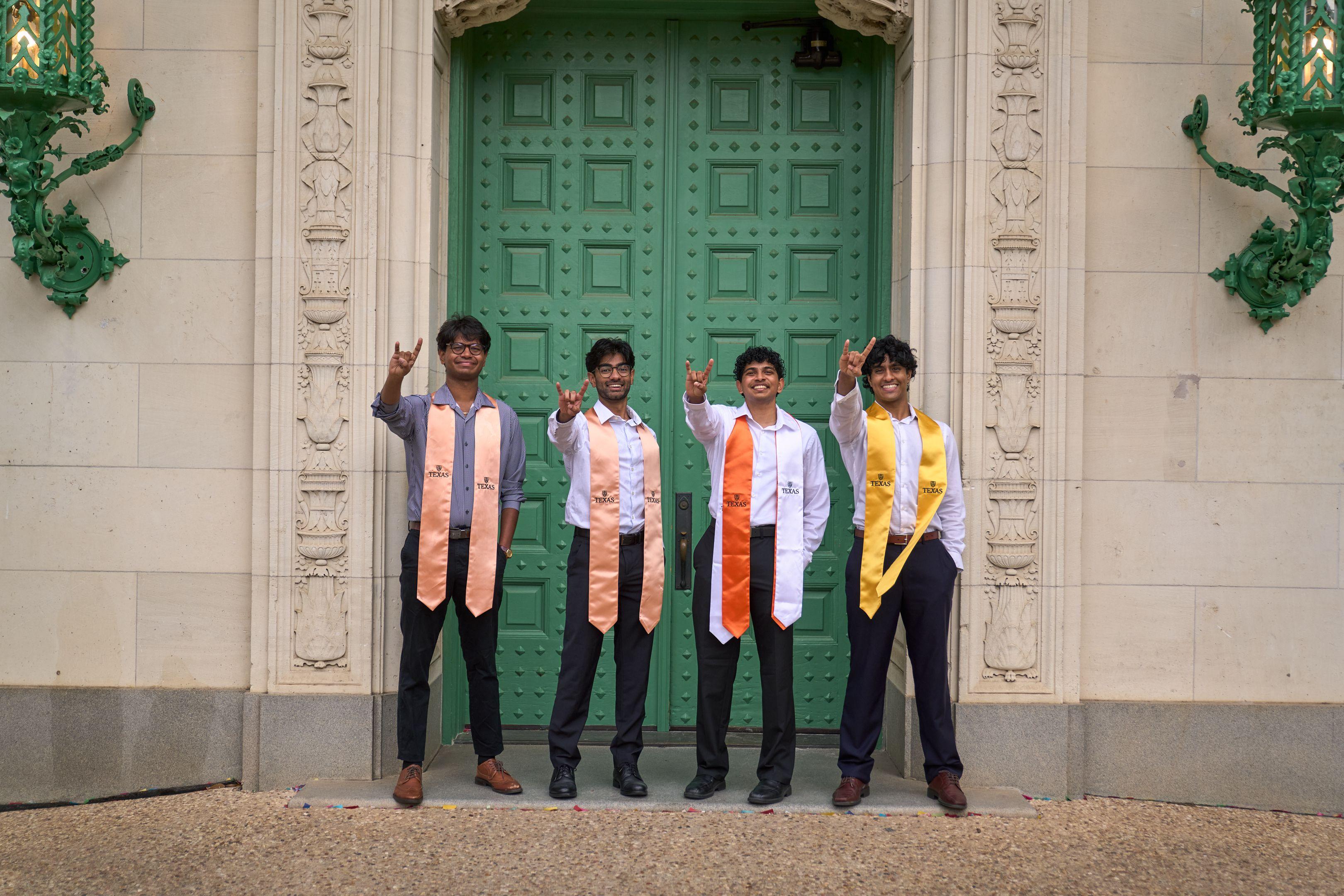 Four graduates in stoles throwing horns in front of the green campus doors — UT Austin photography, Austin Four graduates in stoles throwing horns in front of the green campus doors.