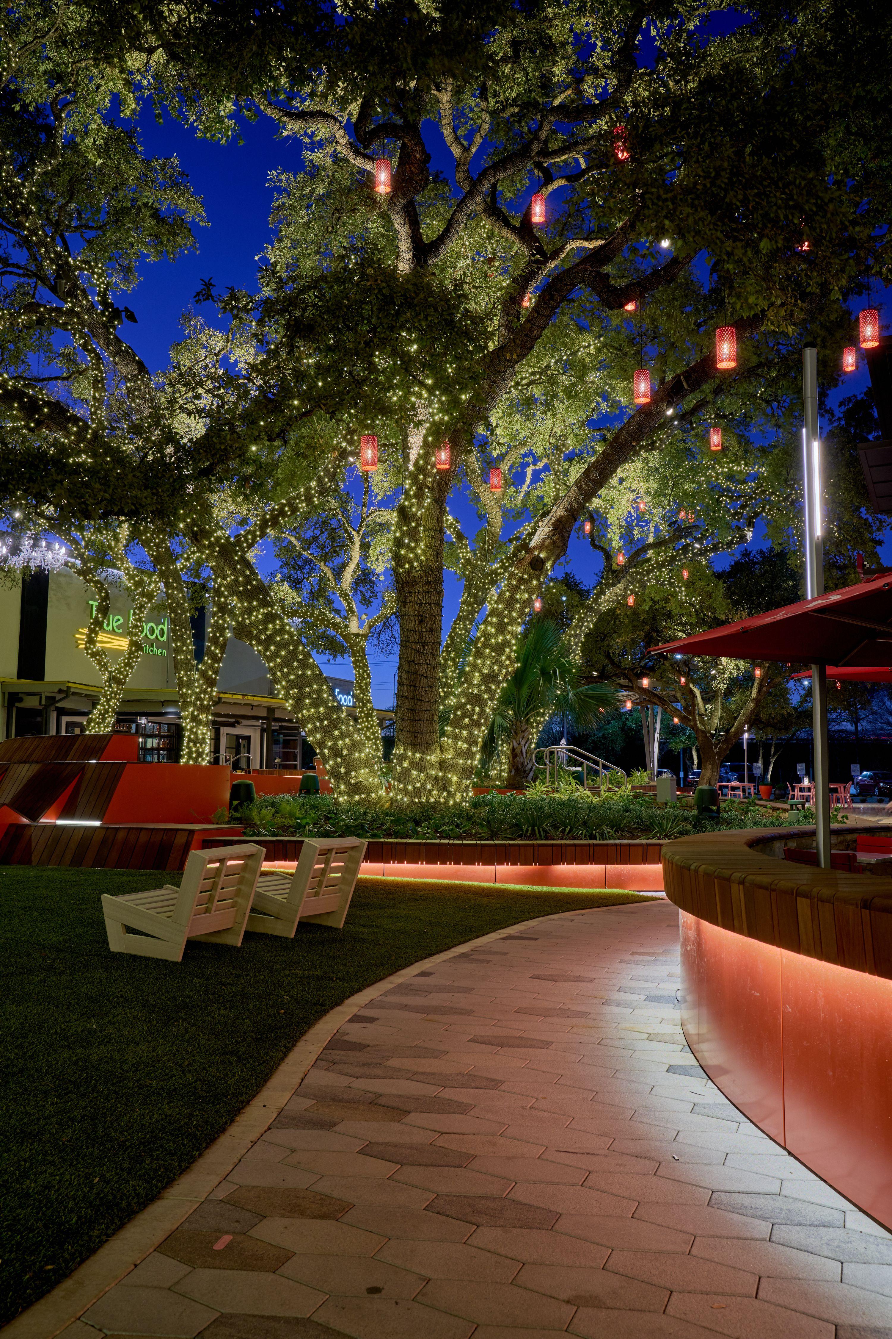 Landscaped courtyard lit at blue hour with lawn games and orange planters — The Domain photography, Austin A landscaped courtyard lit at blue hour with lawn games and orange planters.