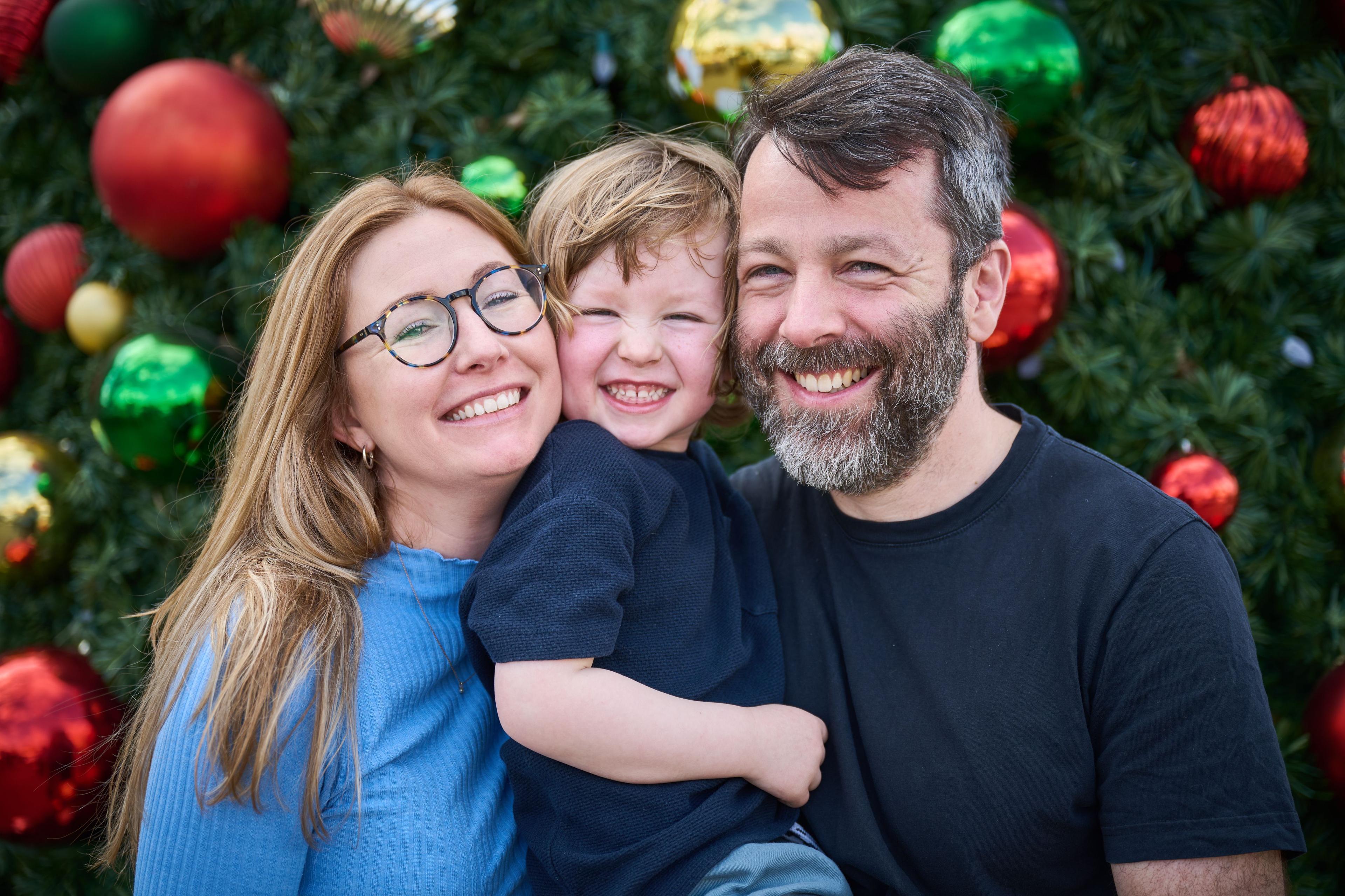 Parents and their small son cheek to cheek in front of a lit Christmas tree — Georgetown Downtown photography, Austin Parents and their small son cheek to cheek in front of a lit Christmas tree.