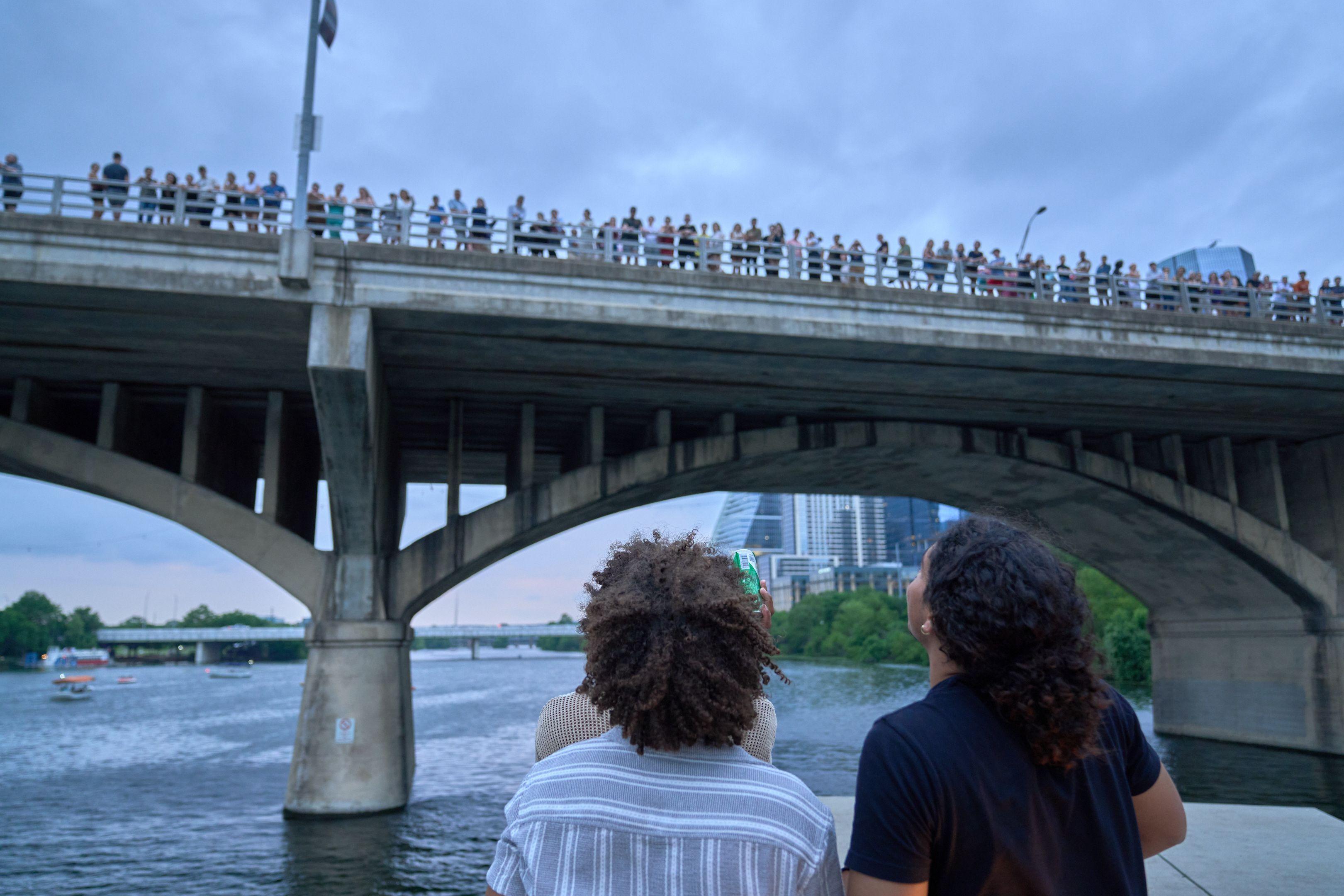 People sitting under a bridge looking out at the water and the city — Adventure & outdoor photography, Austin People sitting under a bridge looking out at the water and the city.