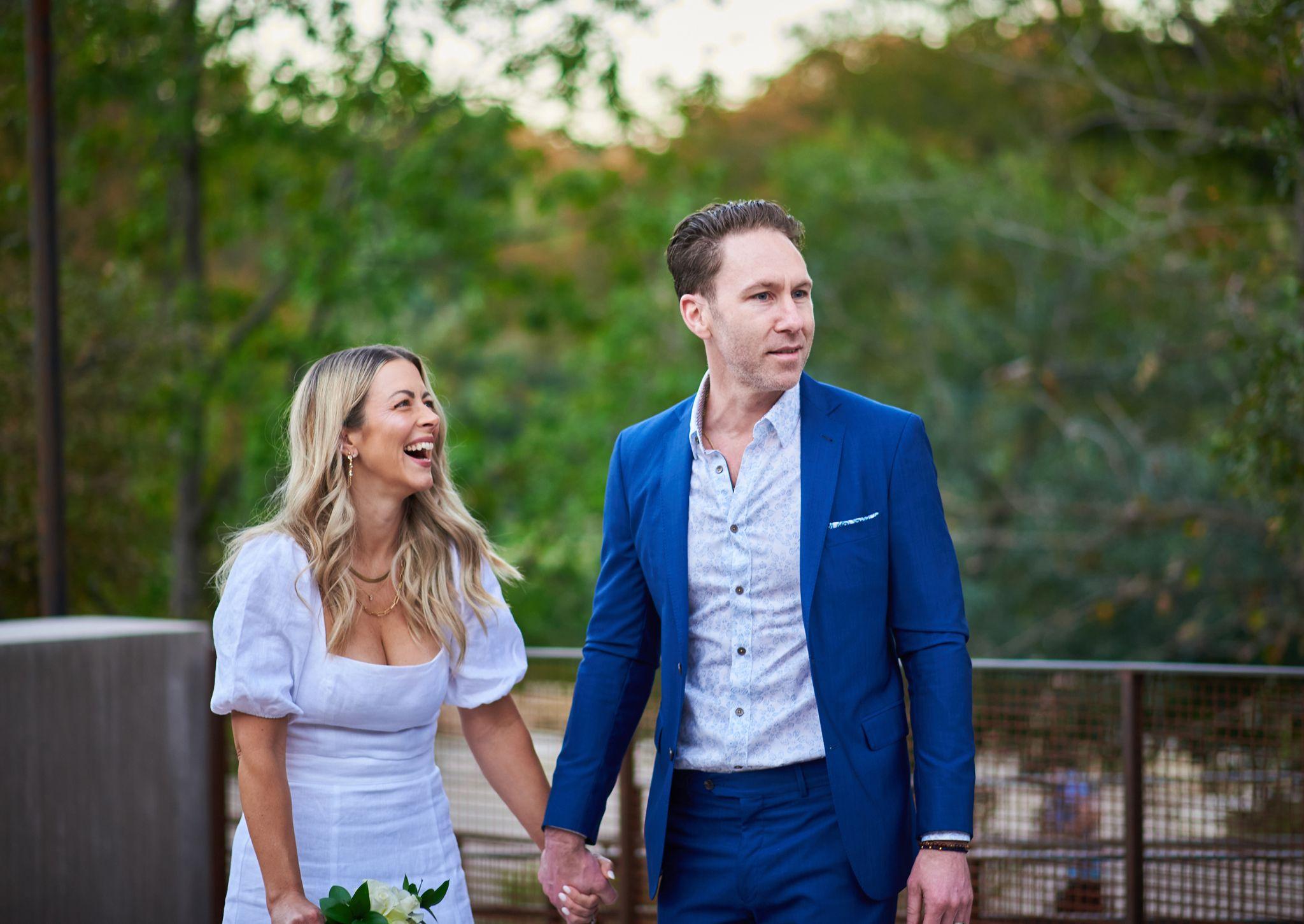 Couple holding hands and laughing outdoors, the groom in a bright blue suit — Pease Park photography, Austin A couple holding hands and laughing outdoors, the groom in a bright blue suit.
