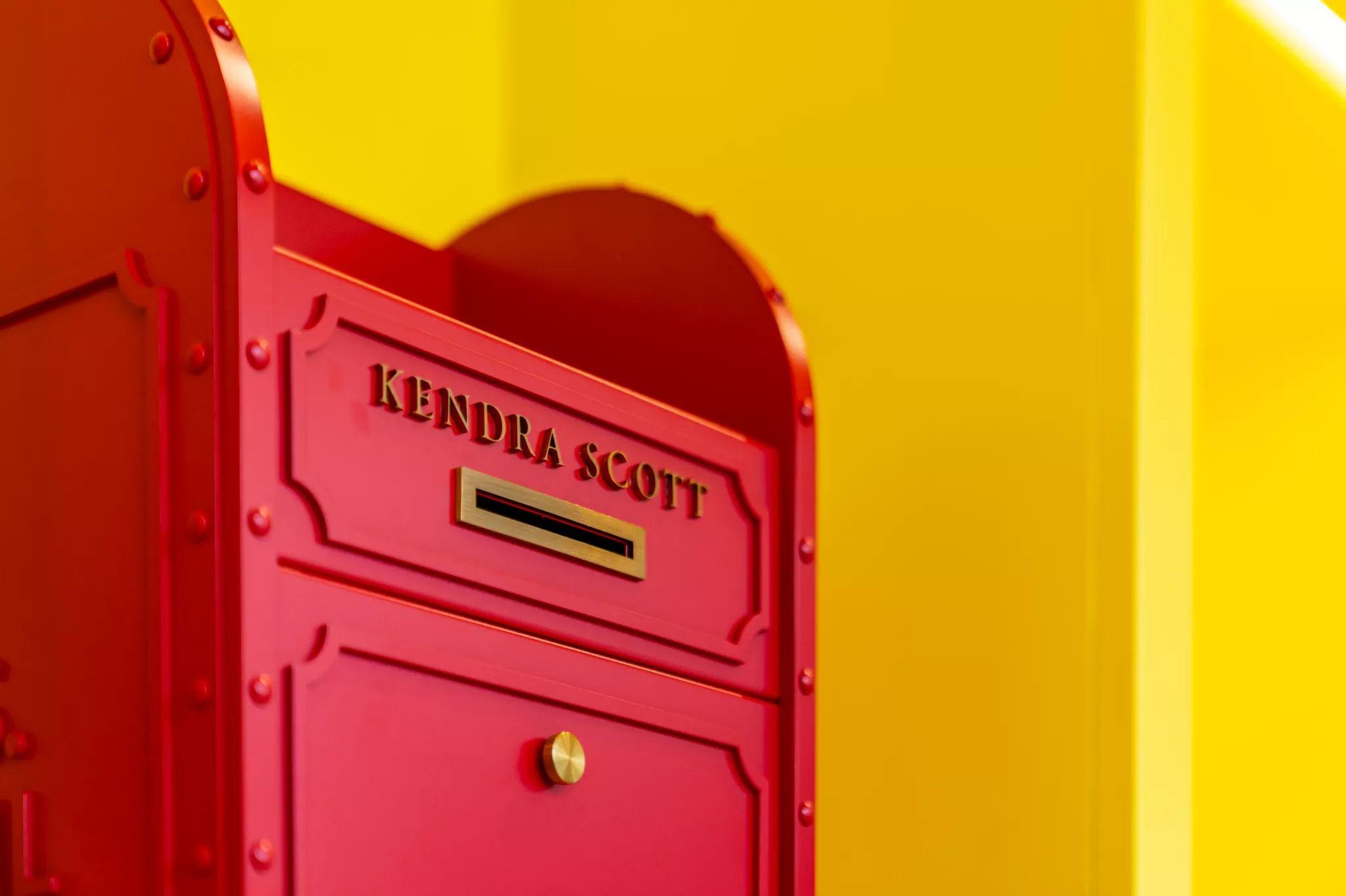 Red Kendra Scott mailbox against a bright yellow wall — Brand activation photography, Austin A red Kendra Scott mailbox against a bright yellow wall.
