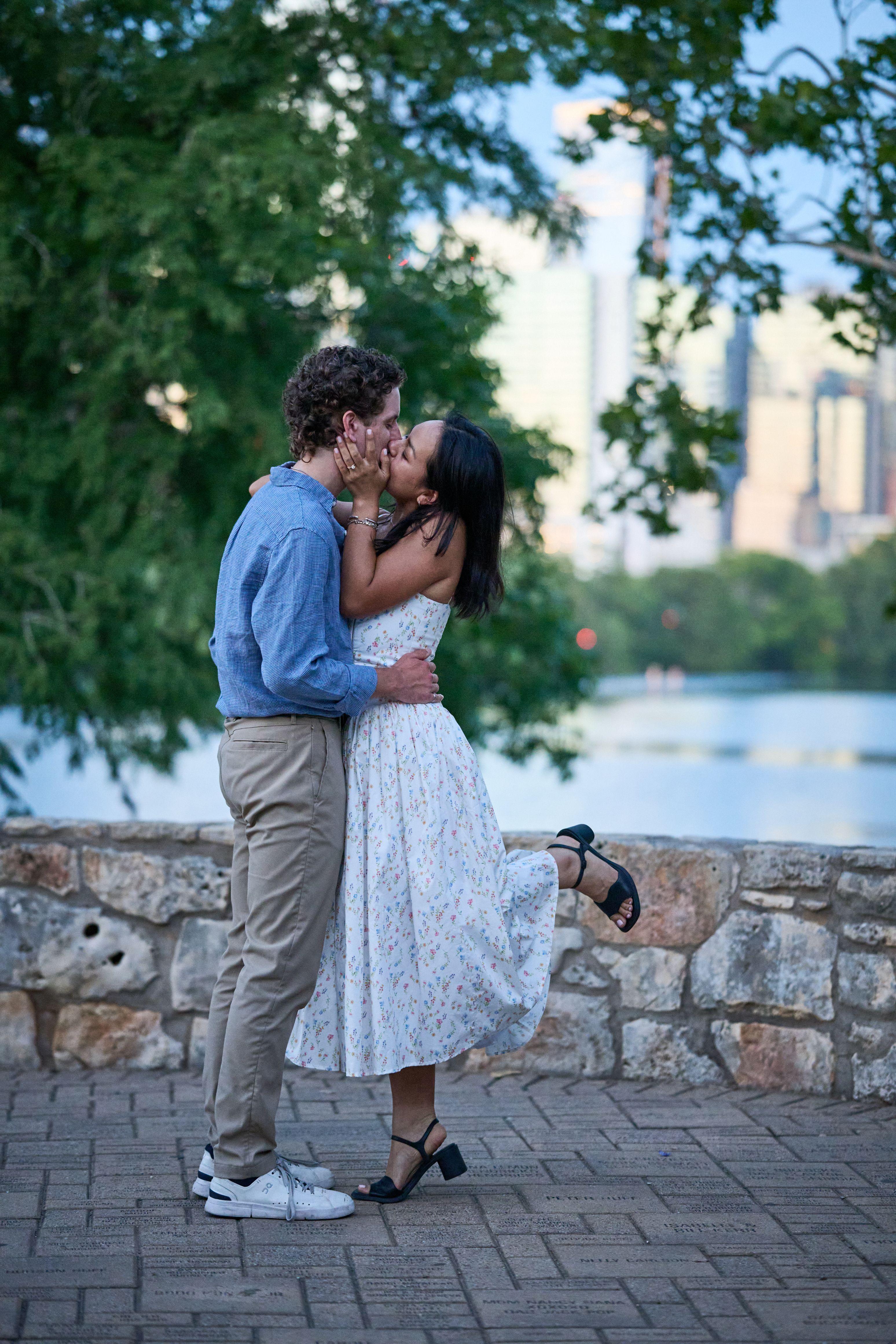 Couple kissing on the stone path at the edge of Zilker Park, Lady Bird Lake — Zilker Park photography, Austin A couple kissing on the stone path at the edge of Zilker Park, Lady Bird Lake and the Austin skyline behind them