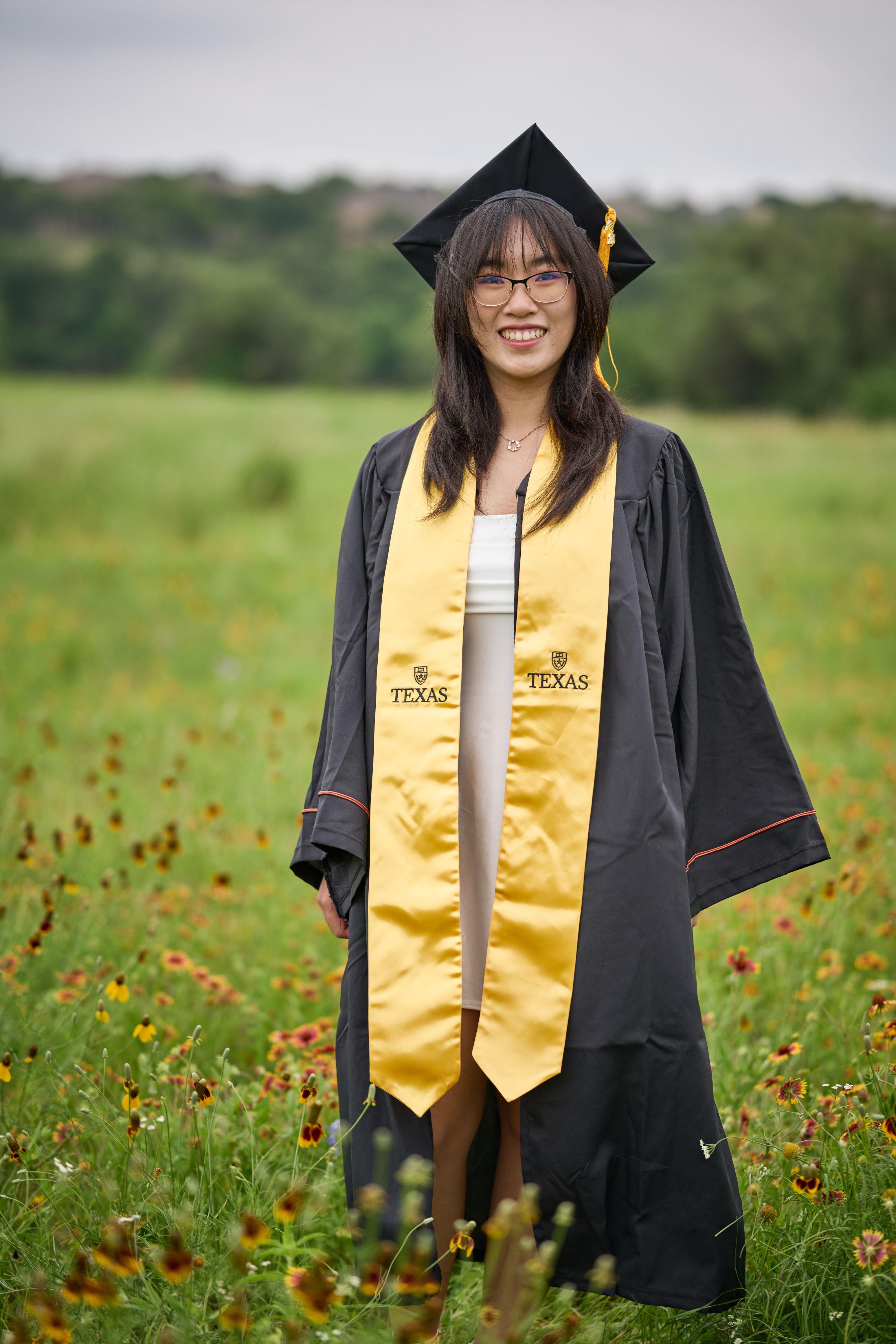 Graduate in cap, gown and gold stole standing among the wildflowers at Brushy Creek Lake Park — Brushy Creek Lake Park photography, Austin A graduate in cap, gown and gold stole standing among the wildflowers at Brushy Creek Lake Park