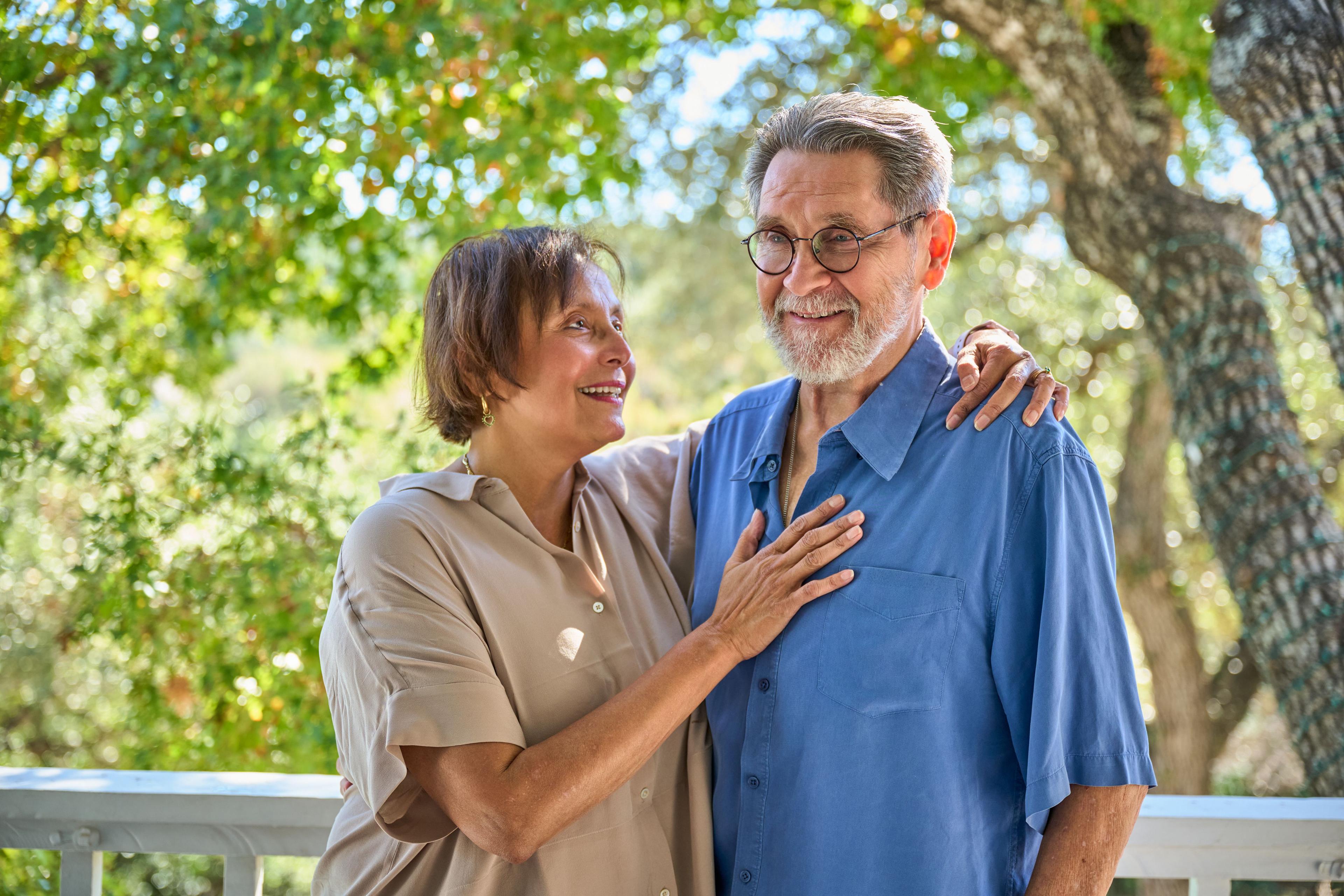 Older couple standing together, her hand on his chest, both laughing — Family Portraits photography, Austin An older couple standing together, her hand on his chest, both laughing.