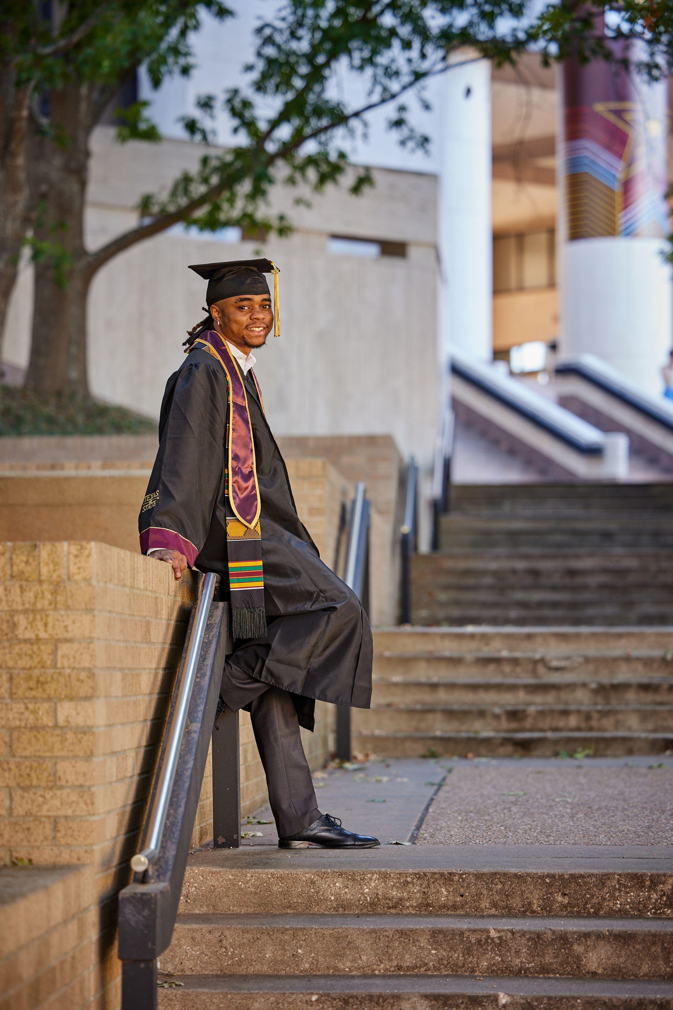 Graduate leaning against the maroon TXST letters on the Texas State campus — Texas State University photography, Austin A graduate leaning against the maroon TXST letters on the Texas State campus