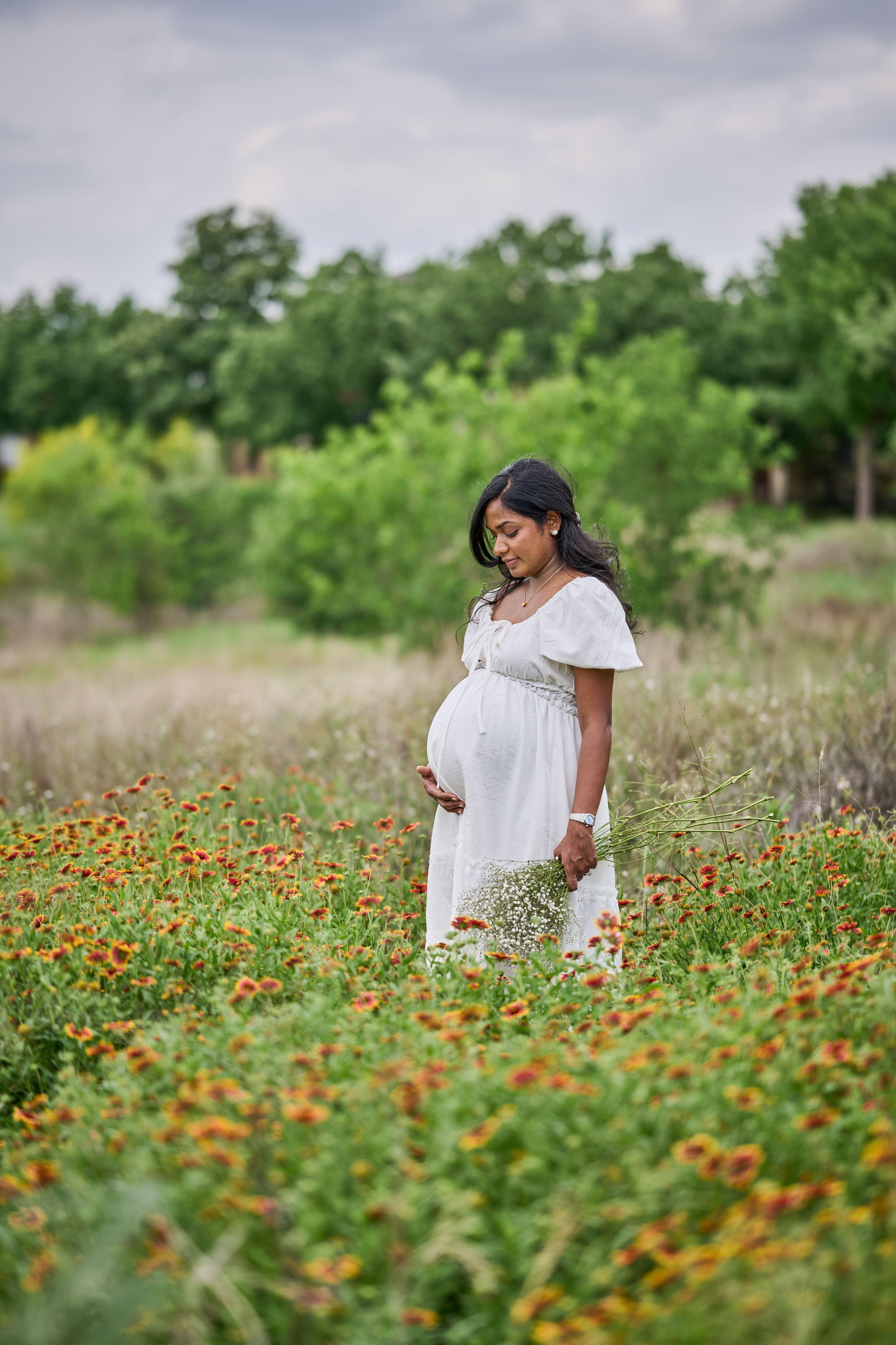 Expectant mother in a white dress standing alone in the orange wildflower meadow at Mueller — Mueller Lake Park & Butterfly Garden photography, Austin An expectant mother in a white dress standing alone in the orange wildflower meadow at Mueller