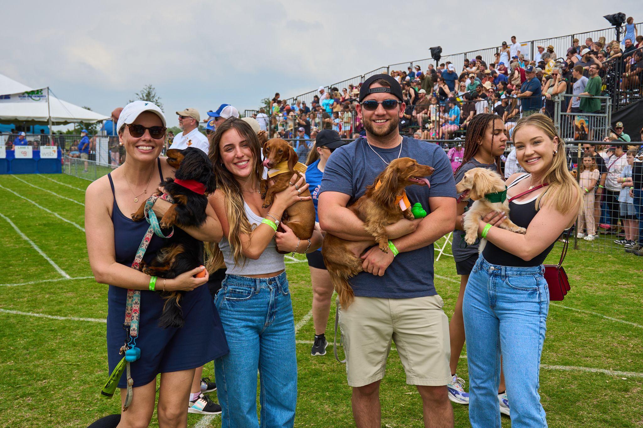 Couple holding two dachshunds in the crowd at a wiener dog race — Festival photography, Austin A couple holding two dachshunds in the crowd at a wiener dog race.