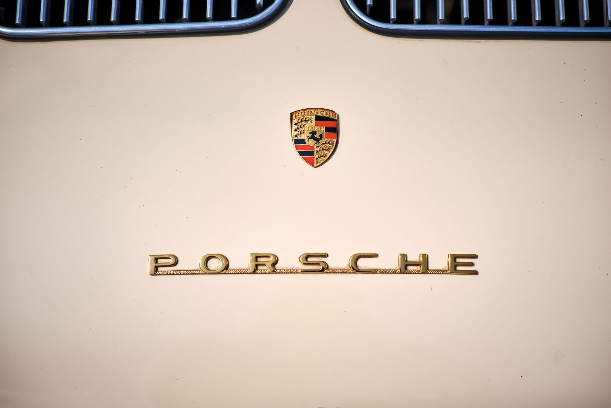 Close detail of the gold PORSCHE script badge on a cream body panel — Automotive photography, Austin A close detail of the gold PORSCHE script badge on a cream body panel.