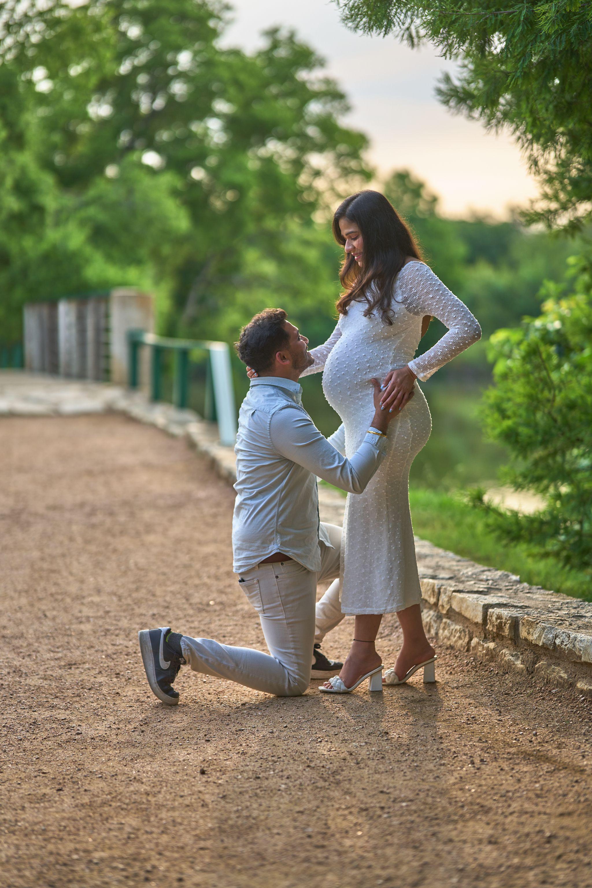 Man kneeling on the path at Mills Pond to kiss an expectant mother's bump — Mills Pond photography, Austin A man kneeling on the path at Mills Pond to kiss an expectant mother's bump