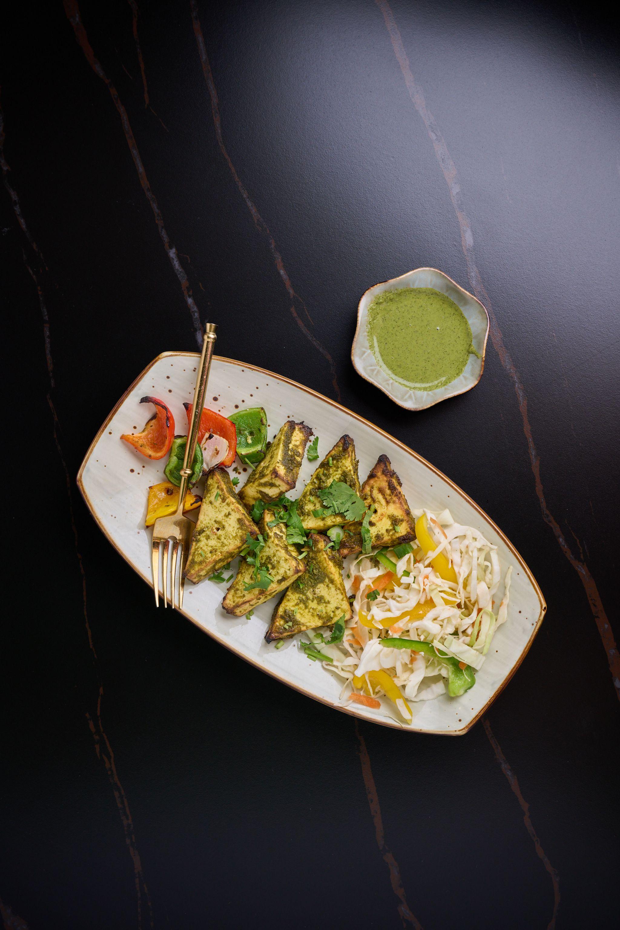Overhead of a plated dish served with green chutney on dark marble — Food & restaurant photography, Austin An overhead of a plated dish served with green chutney on dark marble.