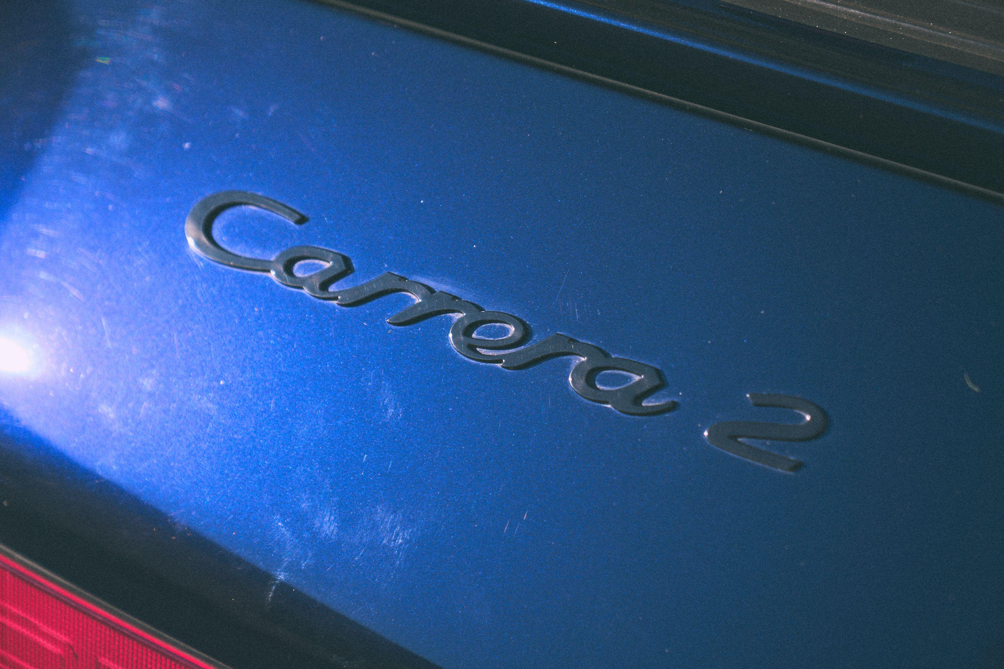 Close detail of a Carrera script badge on deep blue paintwork — Film & vintage photography, Austin A close detail of a Carrera script badge on deep blue paintwork.
