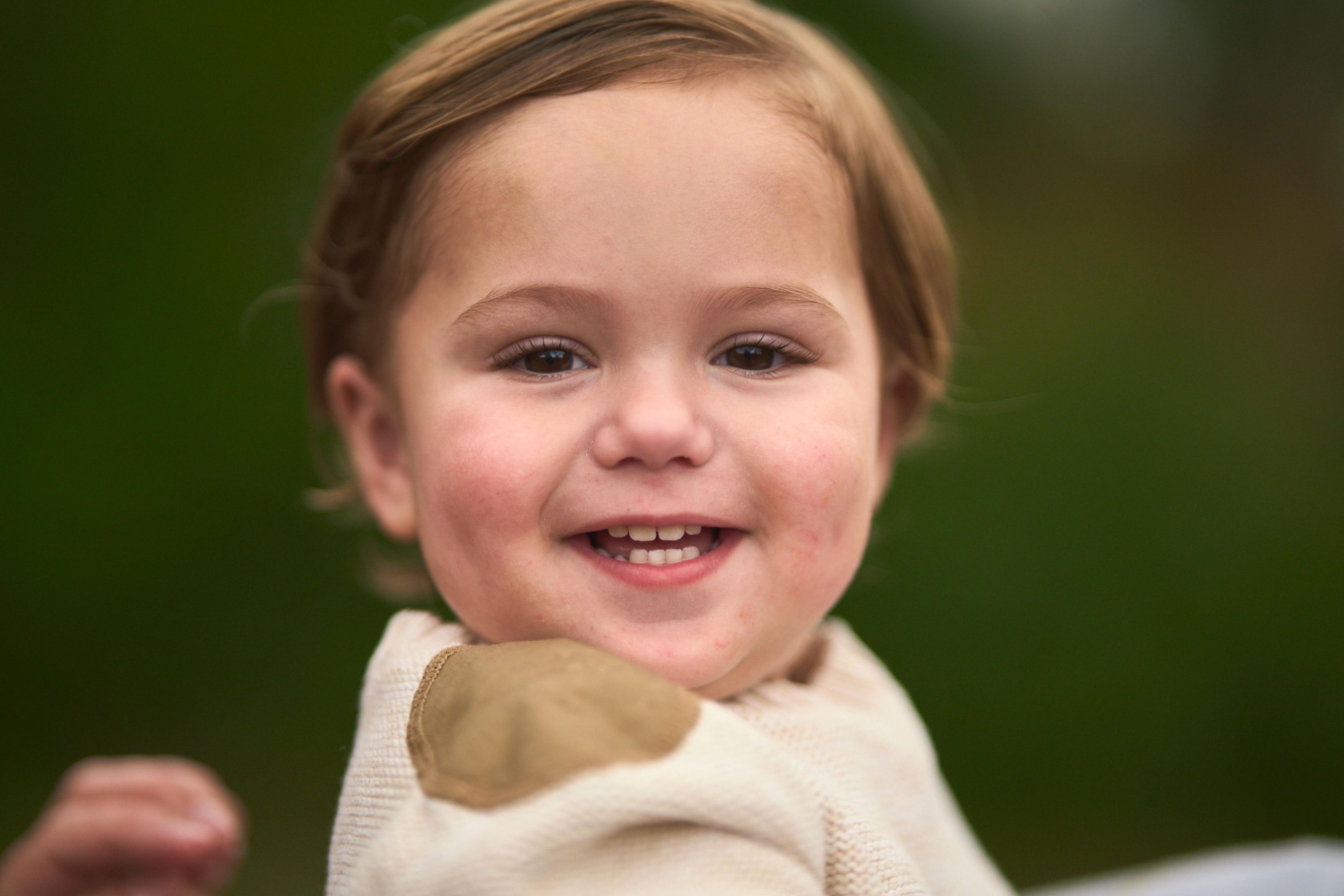 Close frame of a toddler in a cream jumper laughing on the Circle C greenbelt — Circle C Ranch photography, Austin A close frame of a toddler in a cream jumper laughing on the Circle C greenbelt