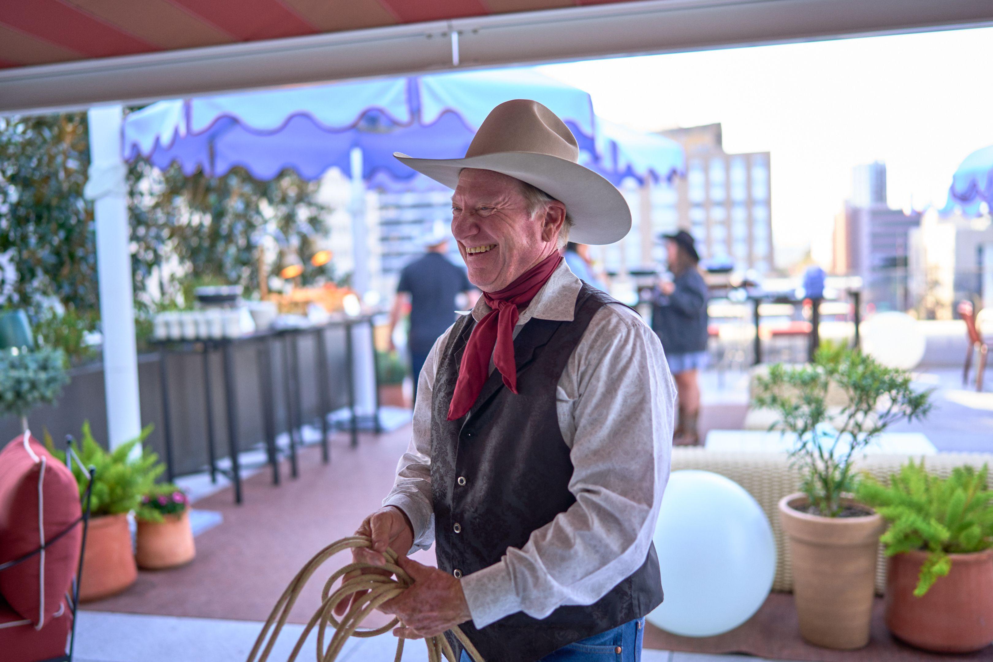 Rope performer in a white cowboy hat working a lariat on a rooftop terrace — Business Parties photography, Austin A rope performer in a white cowboy hat working a lariat on a rooftop terrace.
