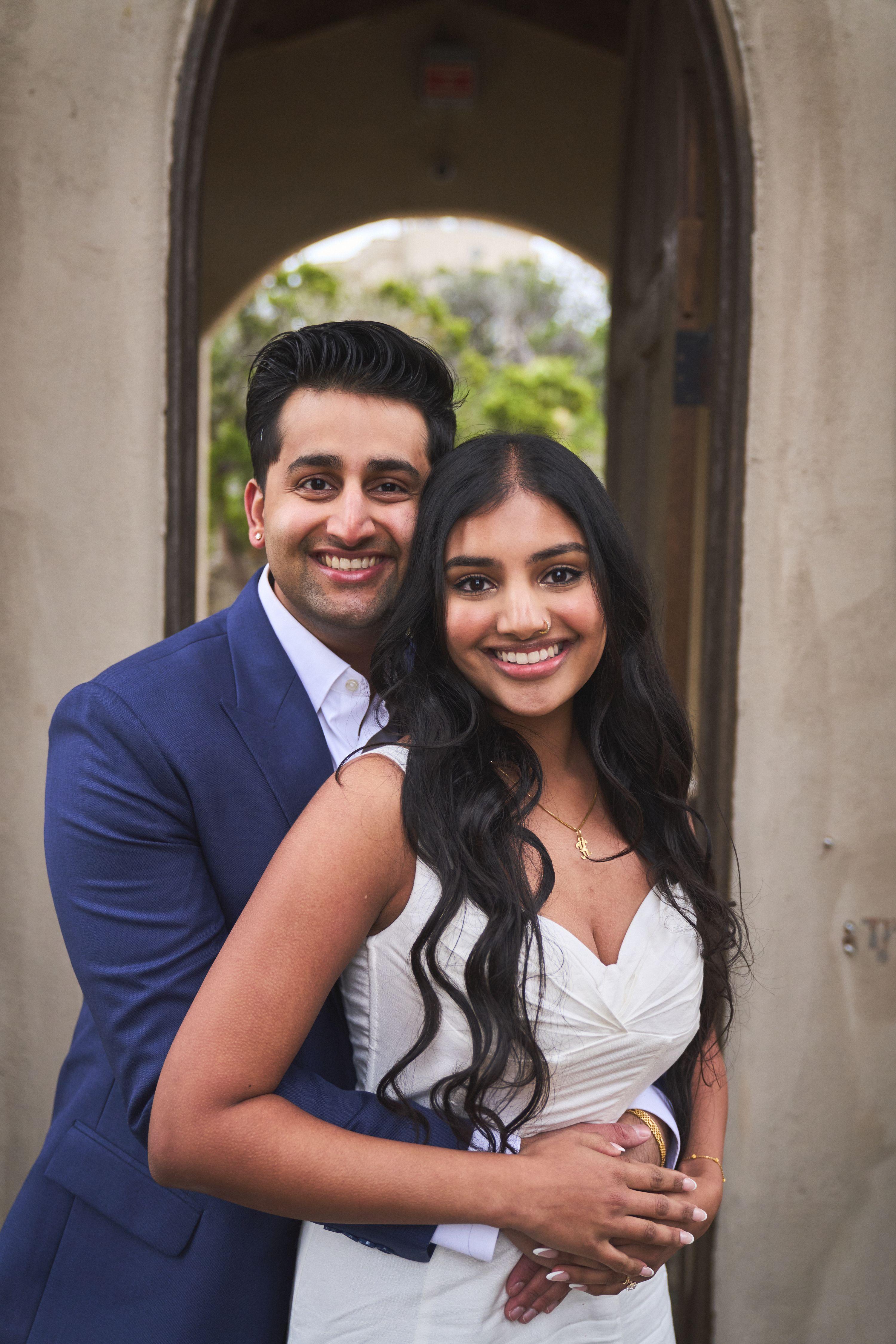 Couple embracing under a stone arch, the groom in navy and the bride in white — Elopements photography, Austin A couple embracing under a stone arch, the groom in navy and the bride in white.