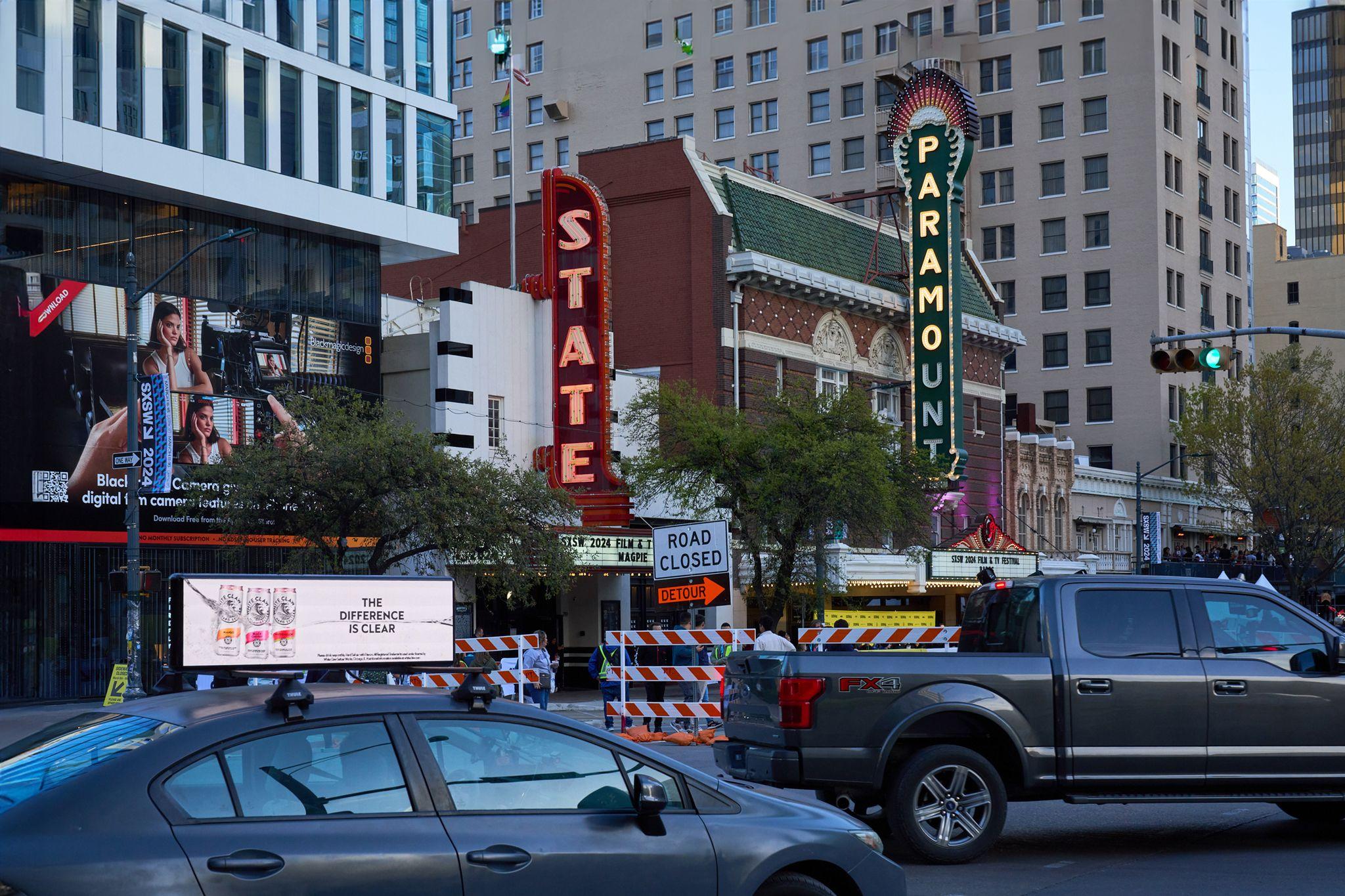 State and Paramount theater marquees on Congress Avenue, with a car-top digital ad — Downtown Austin photography, Austin Downtown Austin