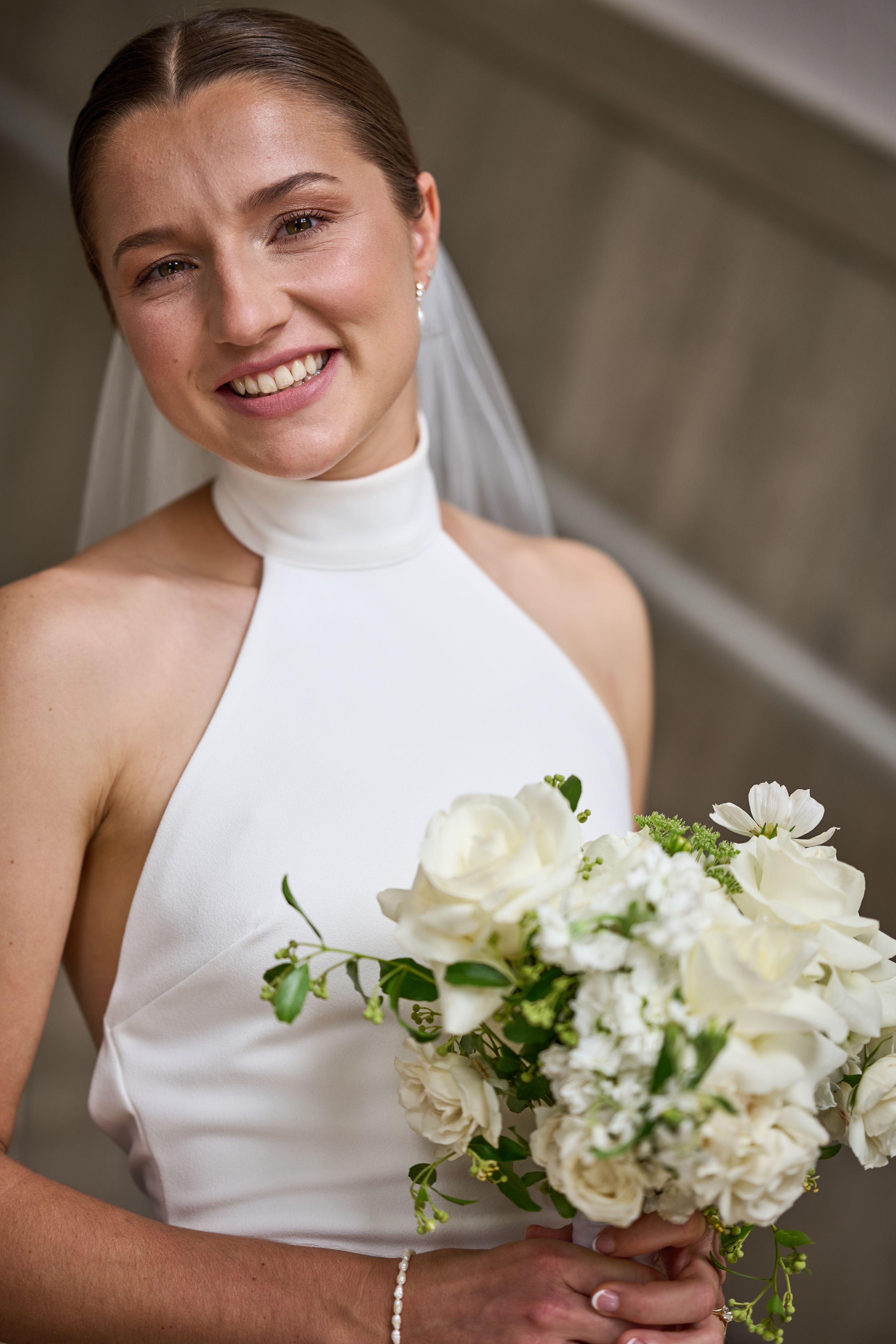 Smiling bride in a white halter gown holding a full white bouquet — Weddings photography, Austin A smiling bride in a white halter gown holding a full white bouquet.