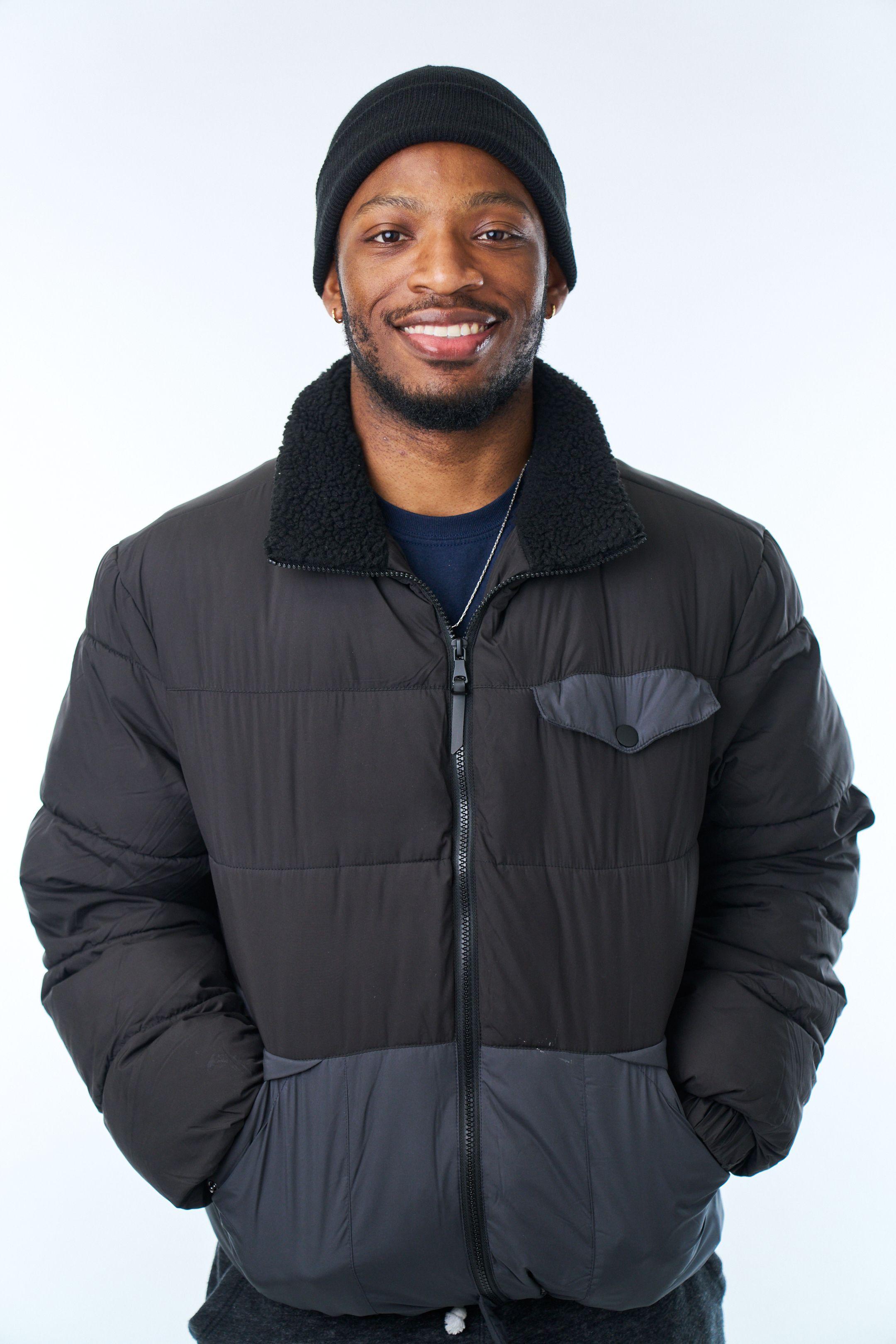 Man in a black puffer jacket and beanie against a white studio background — Commercial photo studio, Austin Man in a black puffer jacket and beanie against a white studio background