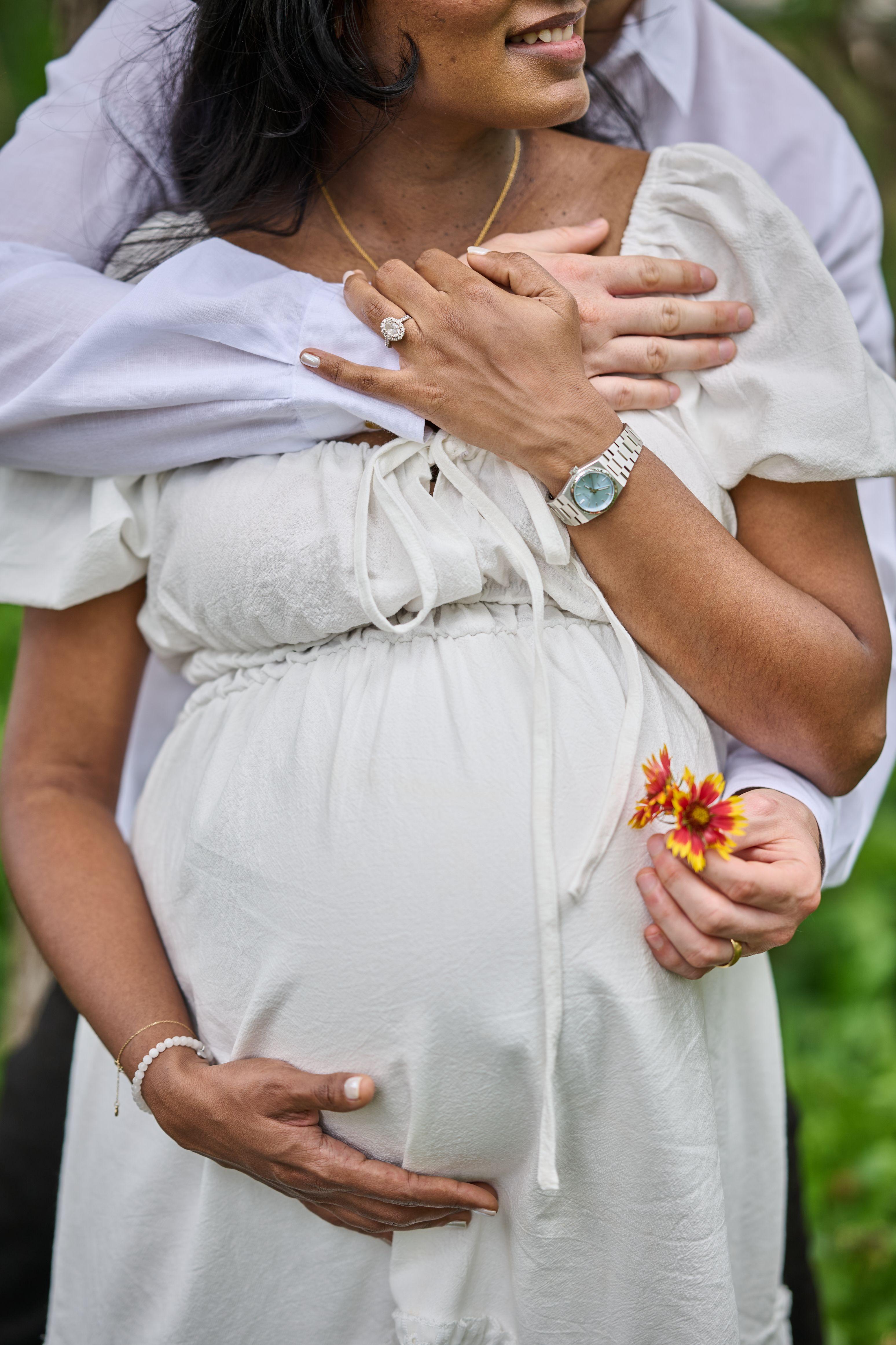 Close detail of a pregnant belly held with a wildflower — Maternity photography, Austin Close detail of a pregnant belly held with a wildflower